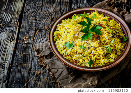 pilaf served on a large beautiful ceramic dish, close-up on the dish on an old dark rough wooden table pilaf served on a large beautiful ceramic dish, close-up on the dish on an old dark rough wooden table 116988110