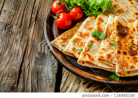 Flatbread made of thin dough with gozleme filling, most often cheese, potatoes or minced meat are added, on a wooden table, concept photo for a cafe menu 116988180