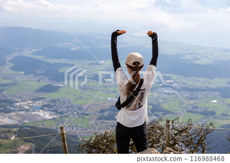 一位戴帽子的年輕女子登上伊吹山,舉起雙手,充滿成就感。 一位戴帽子的年輕女子登上伊吹山,舉起雙手,充滿成就感。 116988468