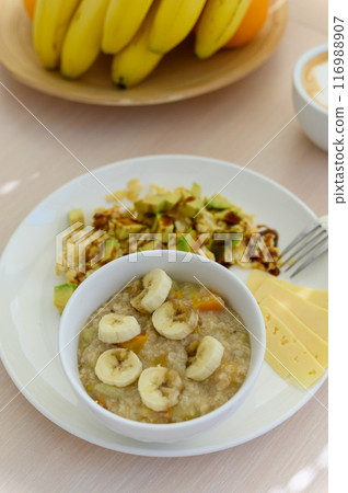 Oatmeal porridge with banana in a white bowl. Healthy breakfast food. Oatmeal porridge with banana in a white bowl. Healthy breakfast food. 116988907