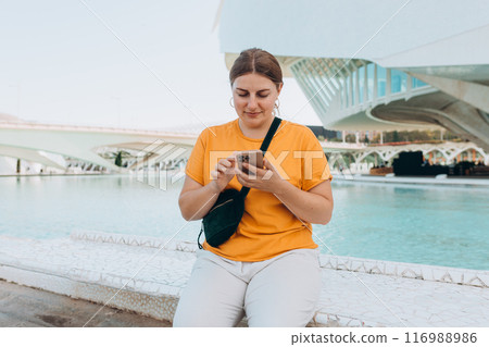 Young traveling woman using phone outdoors. Concept of travel, tourism and vacation in city. Ciudad de las Artes y las Ciencias de Valencia.Valencia City of Arts and Sciences. High quality photo Young traveling woman using phone outdoors. Concept of travel, tourism and vacation in city. Ciudad de las Artes y las Ciencias de Valencia.Valencia City of Arts and Sciences. High quality photo 116988986