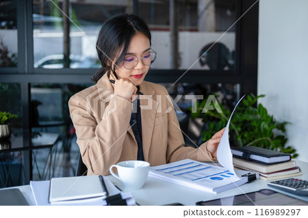 Businesswoman working on analyzing charts and graphs. Businesswoman working on analyzing charts and graphs. 116989297
