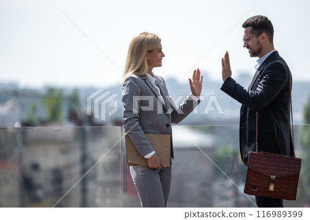 Business partners standing against city buildings and high fiving 116989399