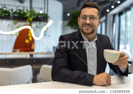 Confident businessman in formalwear having coffee break in cafe Confident businessman in formalwear having coffee break in cafe 116989488