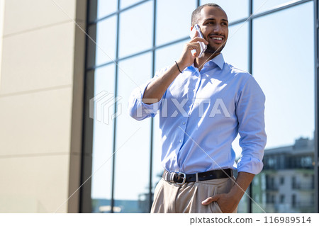 Man wearing formal wear talking on smartphone while walking in city street Man wearing formal wear talking on smartphone while walking in city street 116989514