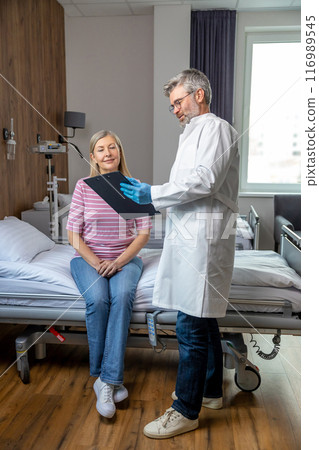 Gray-haired male doctor examining a patient in the admissions 116989545