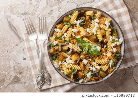 Spicy fusilli pasta with fried eggplant, garlic, feta cheese and breadcrumbs close-up in bowl. Horizontal top view Spicy fusilli pasta with fried eggplant, garlic, feta cheese and breadcrumbs close-up in bowl. Horizontal top view 116989718