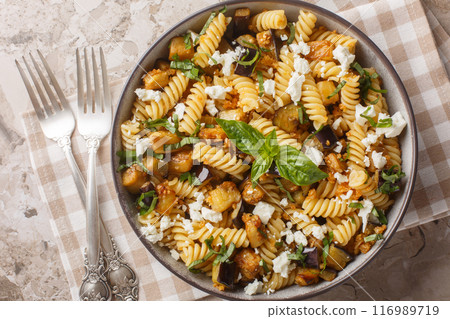 Traditional pasta dish of sauteed eggplant garlic and topped with feta closeup on the bowl. Horizontal top view 116989719