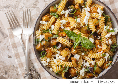 Summer food Fusilli pasta with fried eggplant, garlic and feta cheese close-up in bowl. Horizontal top view 116989720