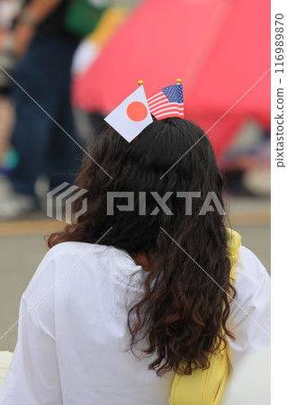 A woman wearing a headband with the stars and stripes and the Japanese flag, view from behind 116989870