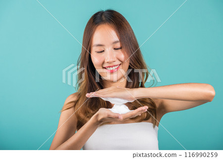 Portrait Asian young woman hands are adorned with white foam mousse studio shot isolated on blue background, beautiful female holds a cleansing foam near her face, Cosmetics beauty skincare 116990259