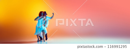 Banner. Couple dancer share their feeling throw salsa moves in neon light against gradient orange background with copy space. Banner. Couple dancer share their feeling throw salsa moves in neon light against gradient orange background with copy space. 116991295