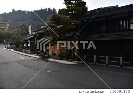 日本岐阜縣的春天。高山市中心的老城區景觀。具有歷史感的日本房屋和宏偉的松樹。 日本岐阜縣的春天。高山市中心的老城區景觀。具有歷史感的日本房屋和宏偉的松樹。 116991330