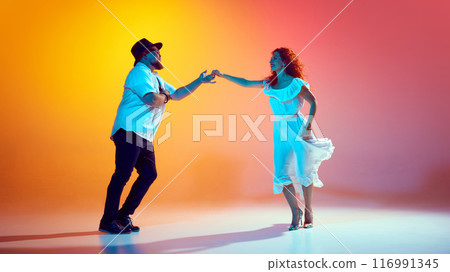 Dancers work on precise coordination and timing in neon light against gradient orange background. Love Latin dance. 116991345