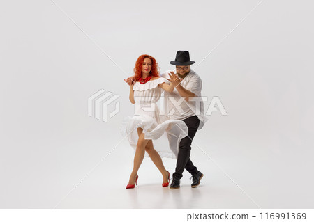 salsa dancers engage in spirited practice, honing their skills and perfecting their footwork against white studio background. 116991369