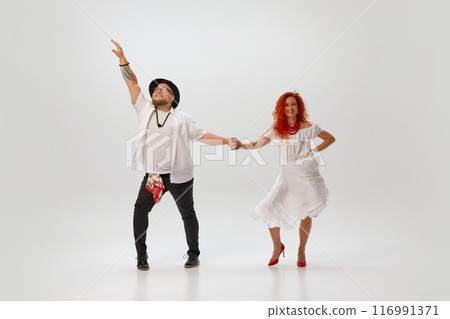 In vibrant salsa training session, couple of dancers synchronize their movements against white studio background. In rhythm of love. 116991371