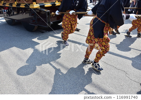Takayama Festival in Spring, Takayama City, Gifu Prefecture, Japan. Men carrying gorgeous floats, wearing flashy costumes and straw sandals. Takayama Festival in Spring, Takayama City, Gifu Prefecture, Japan. Men carrying gorgeous floats, wearing flashy costumes and straw sandals. 116991740