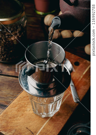 Pouring boiled water into a Vietnamese phin filter 116992788