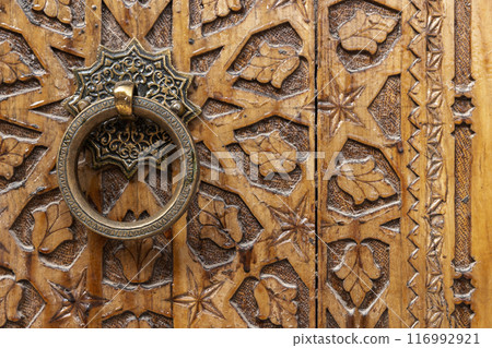 Ancient round copper handle of an old wooden door 116992921