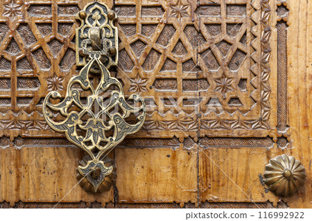 Ancient door knocker of an old wooden gate Ancient door knocker of an old wooden gate 116992922
