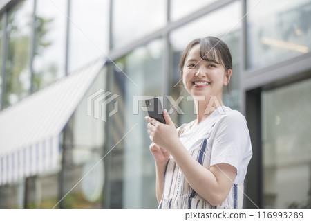 A young woman operating a smartphone 116993289