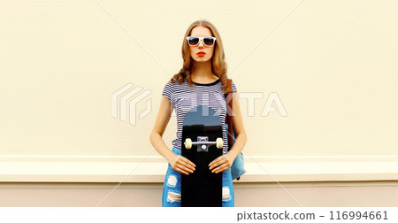 Portrait of stylish young woman with skateboard in the city 116994661