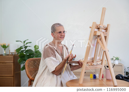 Senior Woman Painting on Canvas at Home Studio with Art Supplies and Plants in Background Senior Woman Painting on Canvas at Home Studio with Art Supplies and Plants in Background 116995000