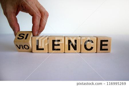 Hand is turning a cubes and changes the word 'silence' to 'violence' or vice versa. Beautiful white background, copy space. Business and social concept. Hand is turning a cubes and changes the word 'silence' to 'violence' or vice versa. Beautiful white background, copy space. Business and social concept. 116995269