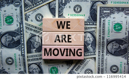 We are moving symbol. Wooden blocks with words 'We are moving'. Beautiful background from dollar bills. Business, we are moving concept, copy space. 116995414