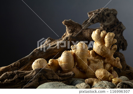 Ginger root with old snags and stones on a black background. 116996307