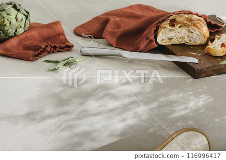 Sliced bread on wooden board, artichoke and stainless still kitchen knife. Kitchen aesthetic concept Sliced bread on wooden board, artichoke and stainless still kitchen knife. Kitchen aesthetic concept 116996417