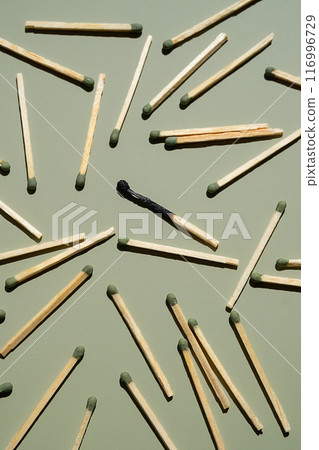 Scattered matches with one burnt matchstick on light green background. 116996729
