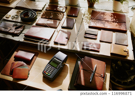 Payment terminal among leather notebooks, card holders and wallets on wooden table 116996871