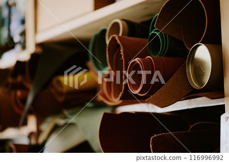 Medium close up of multicolored leather rolls on wooden shelves in workshop Medium close up of multicolored leather rolls on wooden shelves in workshop 116996992