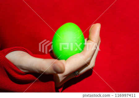 Enigmatic Figure Grasping a Vibrant Green Easter Egg Enigmatic Figure Grasping a Vibrant Green Easter Egg 116997411