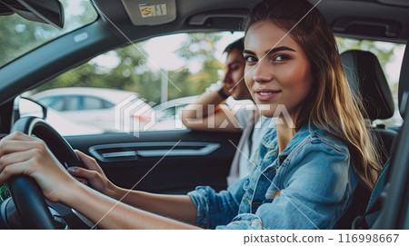 A young woman in a denim jacket smiles confidently while sitting in the driver's seat of a car A young woman in a denim jacket smiles confidently while sitting in the driver's seat of a car 116998667