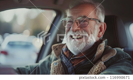 A joyful elderly man with glasses and a white beard, smiling while sitting in a car 116998671