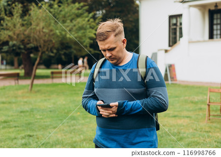 Sad young man receives bad news on the phone outdoors. 30s man using smartphone with serious expression in the park. Negative people emotion 116998766