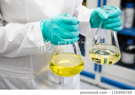 Chemist shaking yellow samples of urine before conducting biochemical analysis 116999199