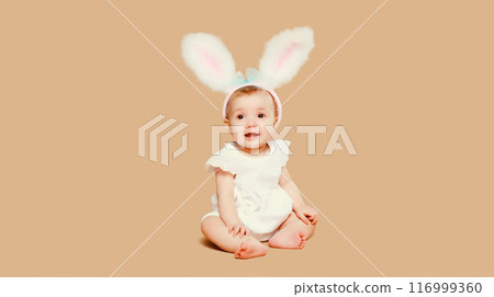 Portrait cute baby with easter rabbit ears sitting on brown studio background 116999360