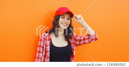 Summer portrait of happy smiling young woman posing in red baseball cap, casual clothes 116999362