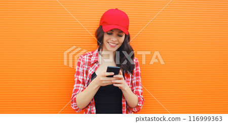 Portrait of happy smiling young woman with mobile phone on colorful orange background Portrait of happy smiling young woman with mobile phone on colorful orange background 116999363