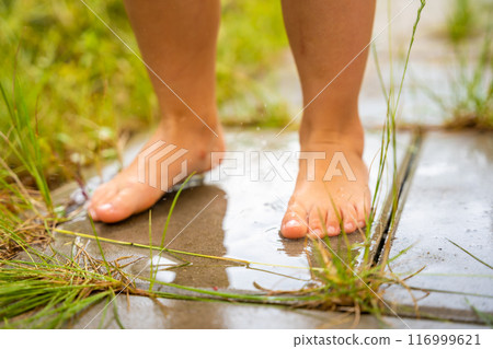 Childs bare feet in water on wet pavement, abnormal heat in the city, water as a way to cool down in hot weather Childs bare feet in water on wet pavement, abnormal heat in the city, water as a way to cool down in hot weather 116999621