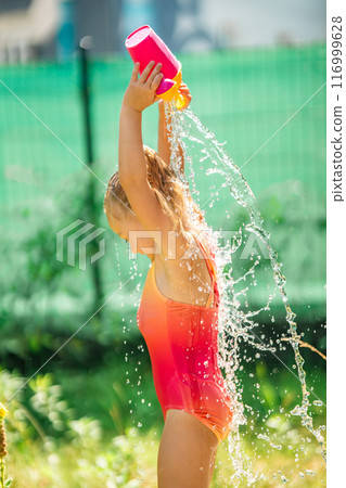 Little girl joyfully plays with water outside on a sunny day, abnormal heat in the city, water as a way to cool down in hot weather Little girl joyfully plays with water outside on a sunny day, abnormal heat in the city, water as a way to cool down in hot weather 116999628