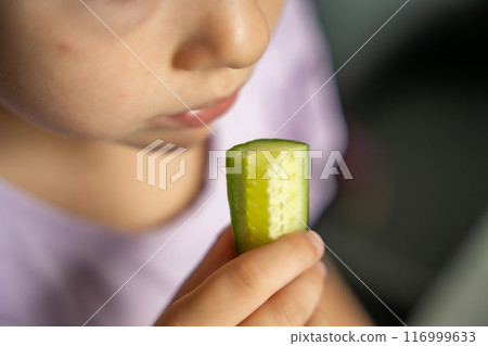 Close up view of little girl eats fresh cucumber. Summer organic food 116999633