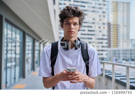 Young guy using smartphone, modern skyscrapers urban style background 116999730