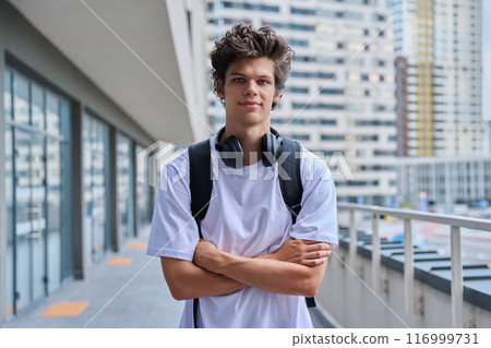 Handsome young man looking at camera outdoors, modern skyscrapers urban style background 116999731