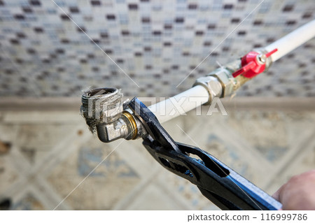 Plumber is disassembling household plumbing in search of leak, he unscrews adapter compression fitting nut with an adjustable wrench. 116999786