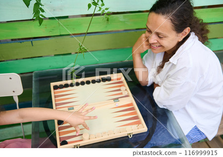 Mother and child enjoying backgammon game outside on a sunny day Mother and child enjoying backgammon game outside on a sunny day 116999915