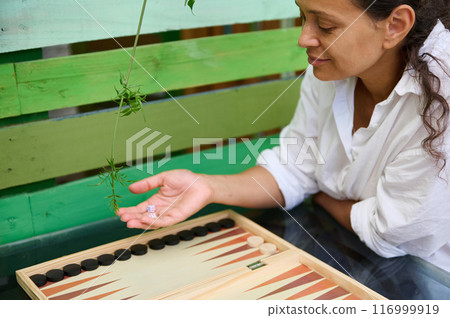 Woman playing backgammon outdoors enjoying a casual game in a relaxed environment Woman playing backgammon outdoors enjoying a casual game in a relaxed environment 116999919